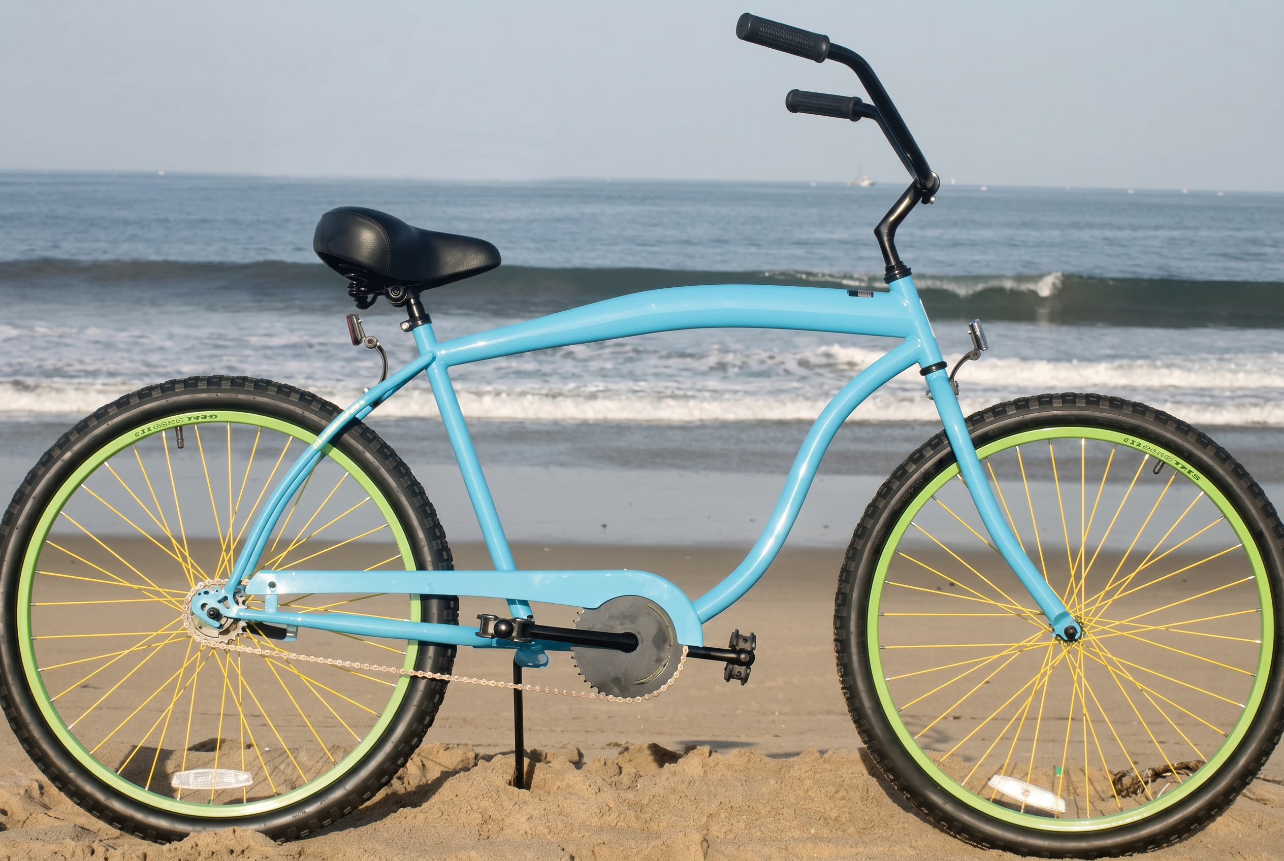 Sky blue beach cruiser with green and yellow wheels on Venice Beach sand